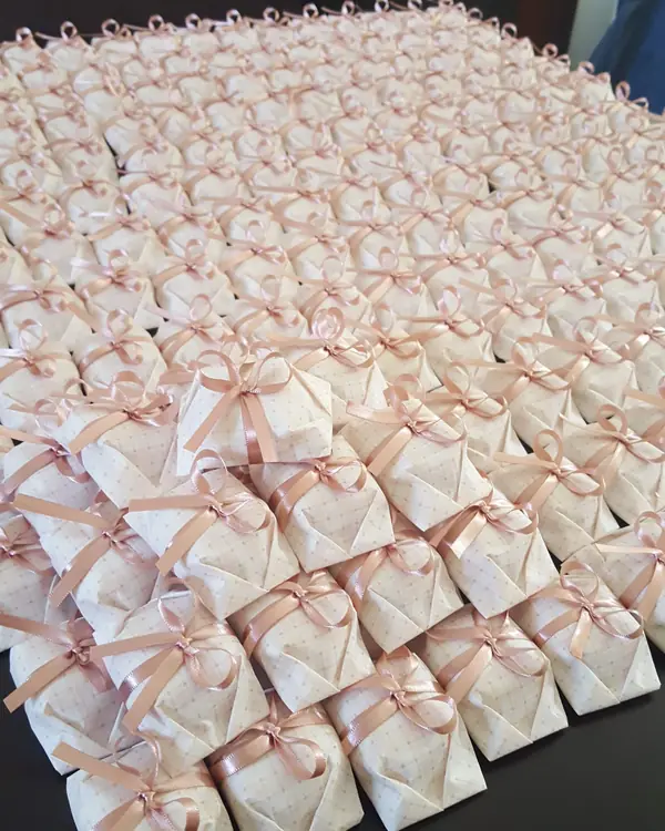 Mesa coberta de bem-casados embalados com fita rosa